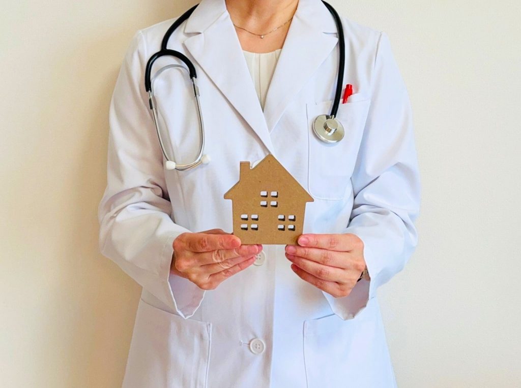 家の模型を持った女性医師の写真