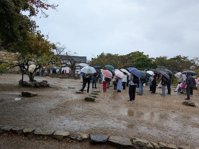 彦根城跡内でガイド役の本学学生から説明を受ける研修旅行参加者の写真